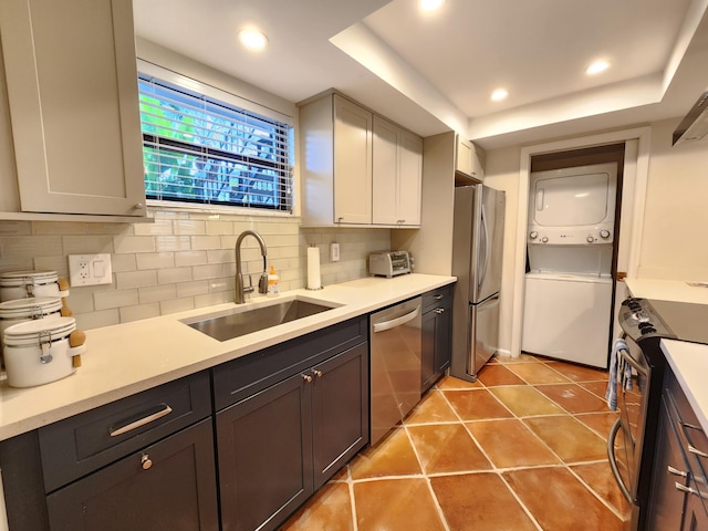 kitchen featuring appliances with stainless steel finishes, backsplash, sink, tile patterned flooring, and stacked washer and dryer