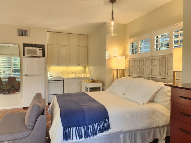 tiled bedroom with white fridge and sink