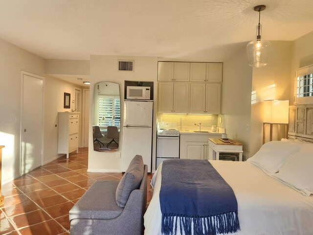 tiled bedroom featuring white refrigerator, multiple windows, and sink