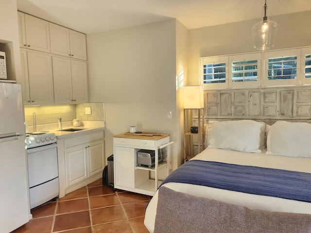 bedroom with dark tile patterned floors, white fridge, and sink