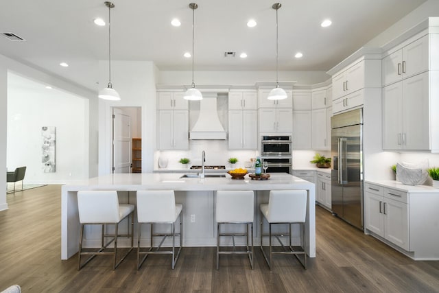 kitchen with stainless steel appliances, a large island, white cabinets, pendant lighting, and premium range hood