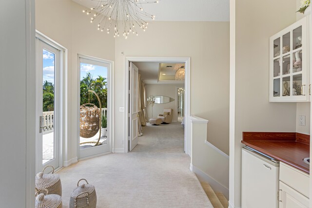 doorway to outside featuring light colored carpet and a notable chandelier