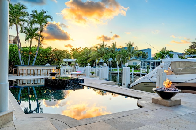 pool at dusk featuring a dock