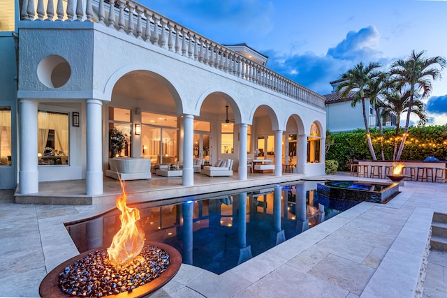 pool at dusk with an in ground hot tub, a patio, and an outdoor fire pit