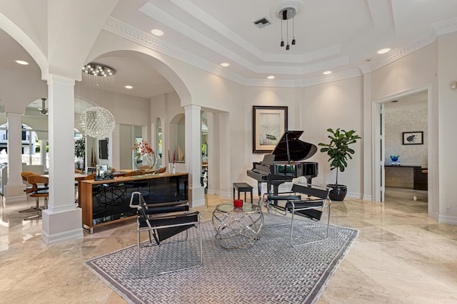 sitting room with a towering ceiling, decorative columns, and a notable chandelier