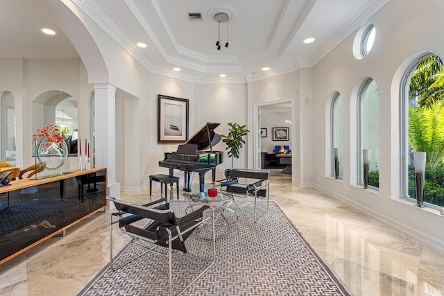 interior space with decorative columns, a raised ceiling, crown molding, and a high ceiling