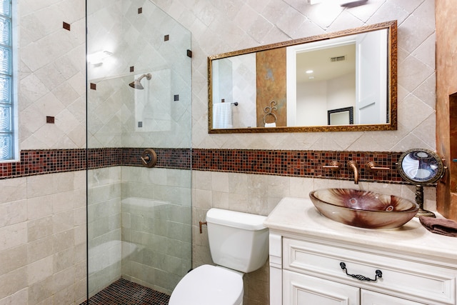 bathroom featuring a tile shower, vanity, tile walls, and toilet