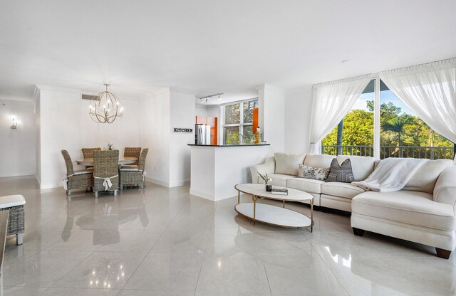 living room with tile floors, ornamental molding, and an inviting chandelier