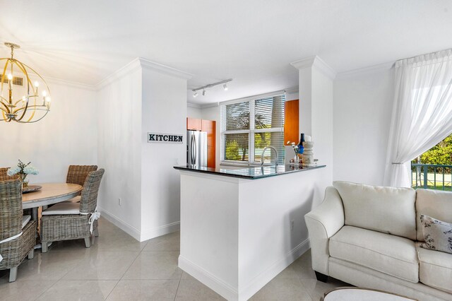 kitchen featuring rail lighting, pendant lighting, an inviting chandelier, light tile floors, and stainless steel refrigerator