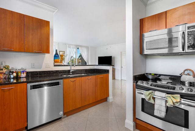 kitchen with crown molding, appliances with stainless steel finishes, dark stone counters, sink, and light tile floors