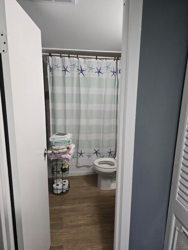 bathroom with shower / tub combo, hardwood / wood-style flooring, and toilet