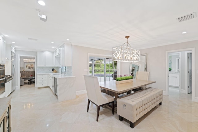 dining room with a notable chandelier, crown molding, and sink