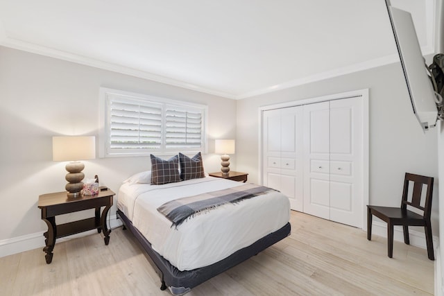 bedroom featuring light hardwood / wood-style floors, ornamental molding, and a closet