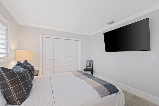 bedroom with hardwood / wood-style flooring, crown molding, and a closet