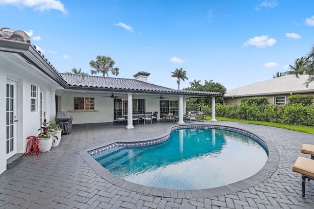 view of swimming pool with ceiling fan, a patio area, and grilling area