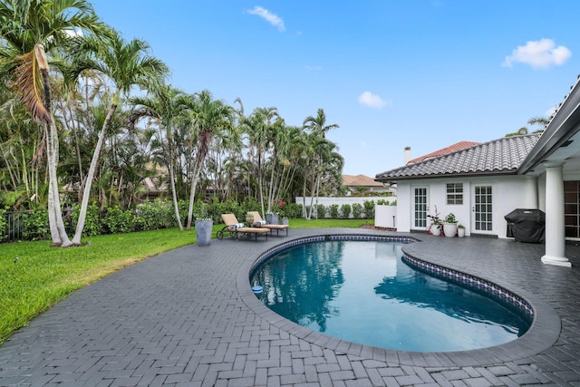 view of pool with a lawn, grilling area, and a patio