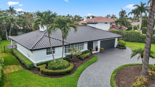 mediterranean / spanish home featuring a garage and a front lawn