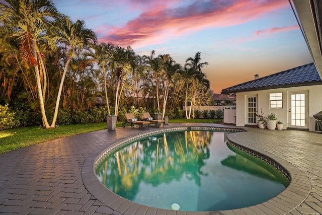 pool at dusk featuring a patio area