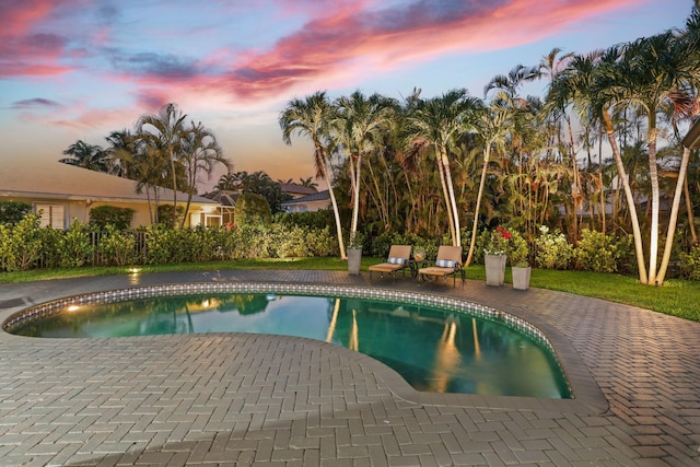 pool at dusk featuring a patio area