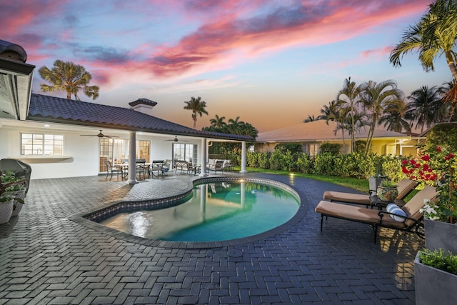 pool at dusk featuring ceiling fan, french doors, and a patio