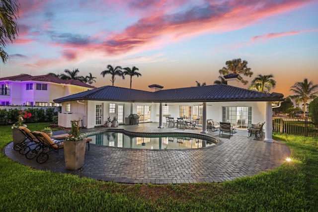 back house at dusk with a fenced in pool and a patio