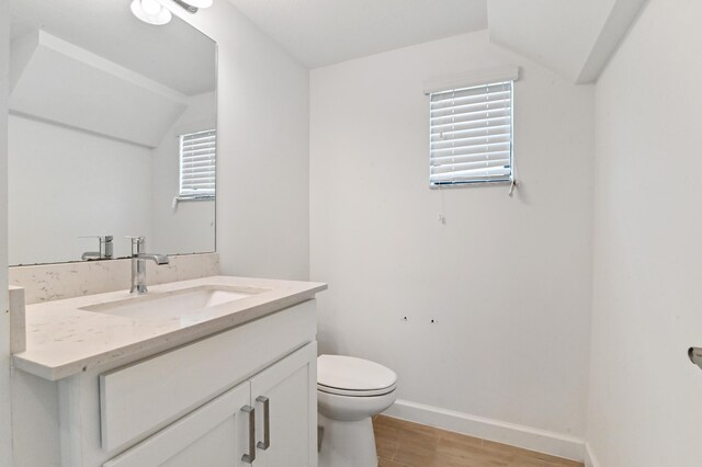 bathroom featuring vanity, wood-type flooring, lofted ceiling, toilet, and plenty of natural light