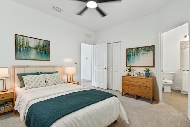 bedroom with connected bathroom, light carpet, ceiling fan, and a closet