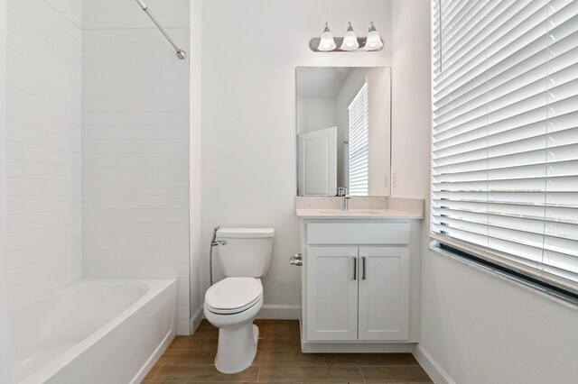 full bathroom with wood-type flooring, a wealth of natural light, tiled shower / bath combo, vanity, and toilet