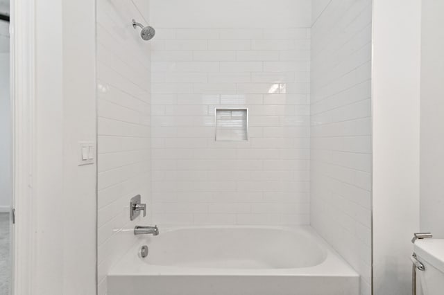 bathroom featuring tiled shower / bath and toilet