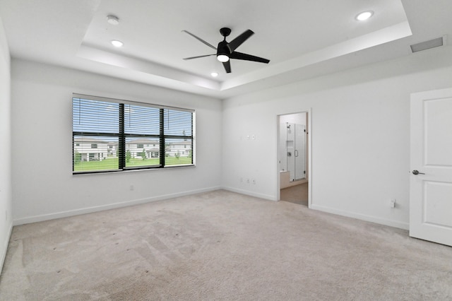 unfurnished room with a tray ceiling, ceiling fan, and light colored carpet