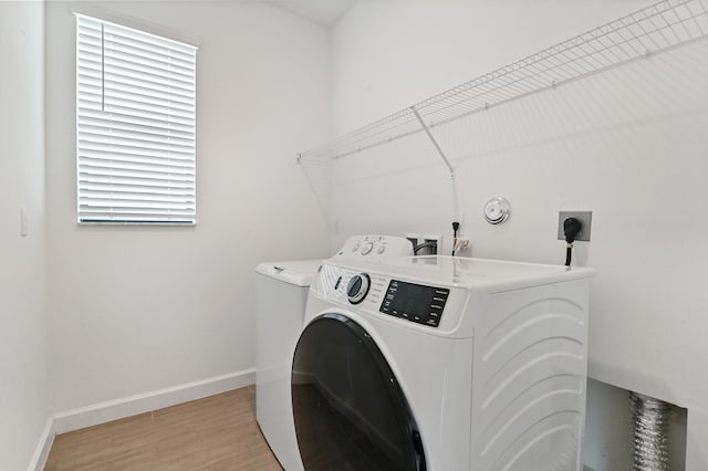 clothes washing area with light wood-type flooring, plenty of natural light, and washer and dryer