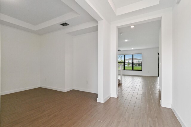 empty room with a raised ceiling and light hardwood / wood-style floors