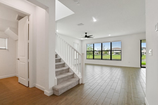 stairway with ceiling fan and hardwood / wood-style flooring