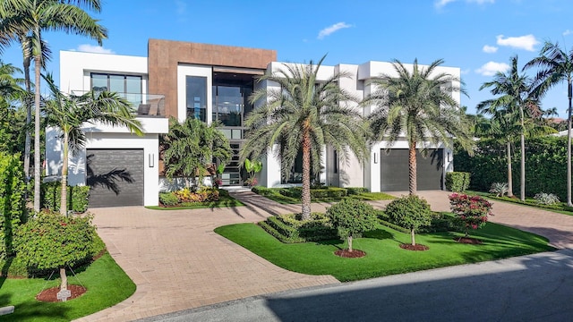 view of front facade with a balcony, a front lawn, and a garage