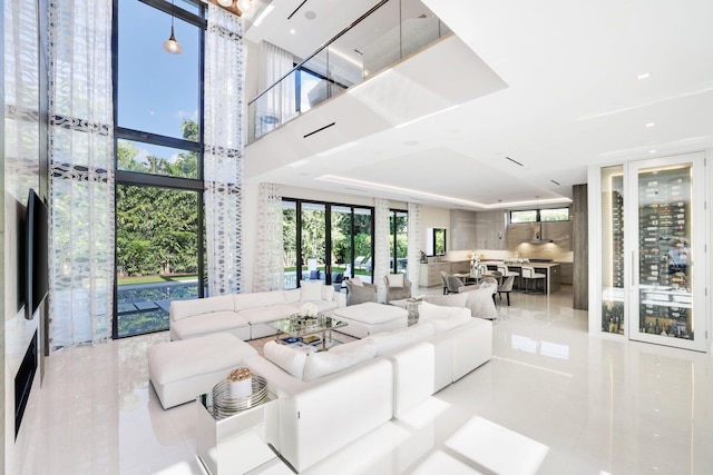 living room with floor to ceiling windows, light tile patterned floors, and a high ceiling