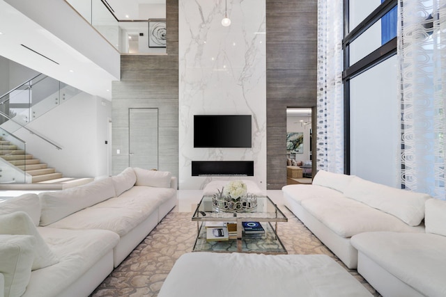 living room with ceiling fan, a high end fireplace, and a high ceiling