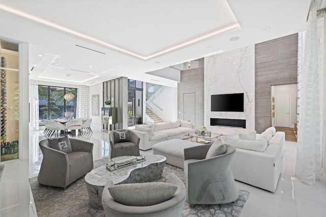 living room featuring a premium fireplace, tile walls, and a tray ceiling