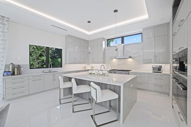 kitchen with pendant lighting, a center island, a tray ceiling, and a healthy amount of sunlight