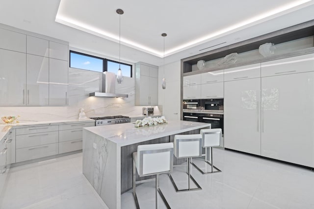 kitchen featuring decorative backsplash, a center island, decorative light fixtures, and wall chimney range hood