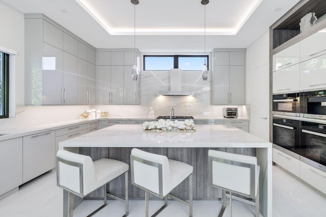 kitchen with a raised ceiling, backsplash, and decorative light fixtures