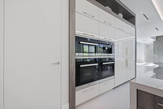 kitchen with light tile patterned floors, stainless steel appliances, and white cabinetry