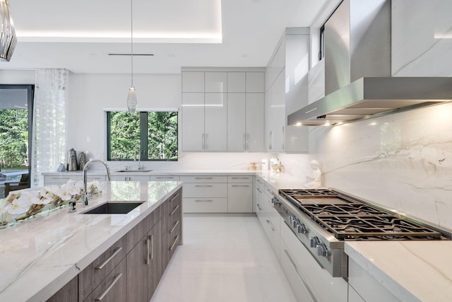 kitchen featuring backsplash, stainless steel cooktop, wall chimney exhaust hood, and sink