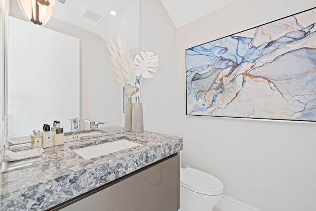 bathroom with vanity, vaulted ceiling, and toilet