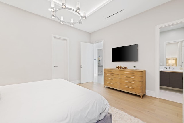 bedroom with a chandelier, light hardwood / wood-style floors, and ensuite bathroom