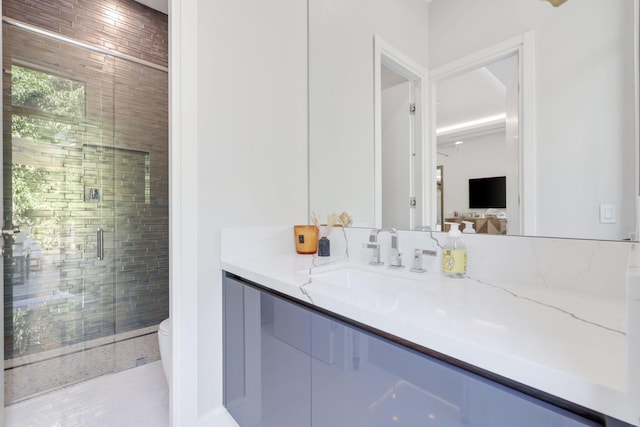 bathroom featuring a shower with door, vanity, and toilet