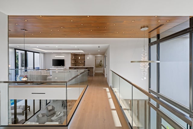 hallway with wood ceiling, light hardwood / wood-style floors, and a wall of windows