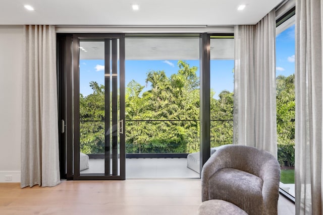 doorway with a healthy amount of sunlight, floor to ceiling windows, and light hardwood / wood-style flooring