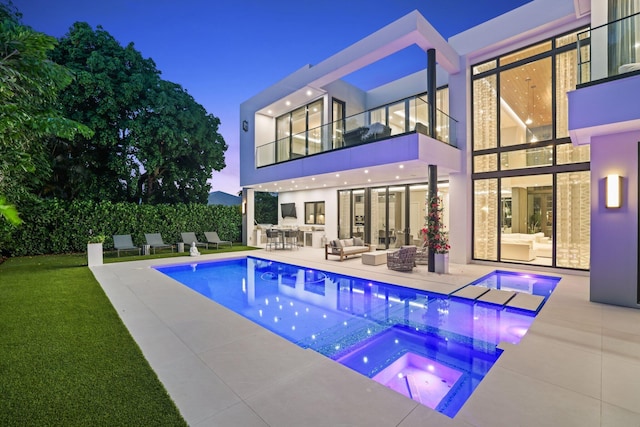 pool at dusk featuring an in ground hot tub, an outdoor hangout area, and a patio