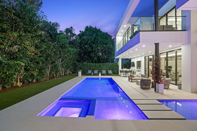 pool at dusk featuring an outdoor living space, a patio area, and an in ground hot tub