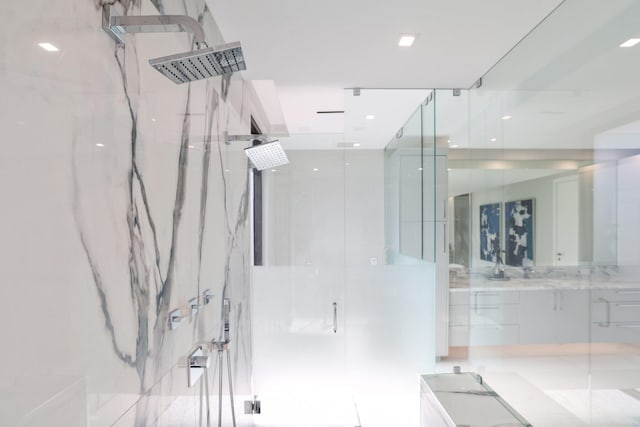 bathroom with a tile shower and vanity